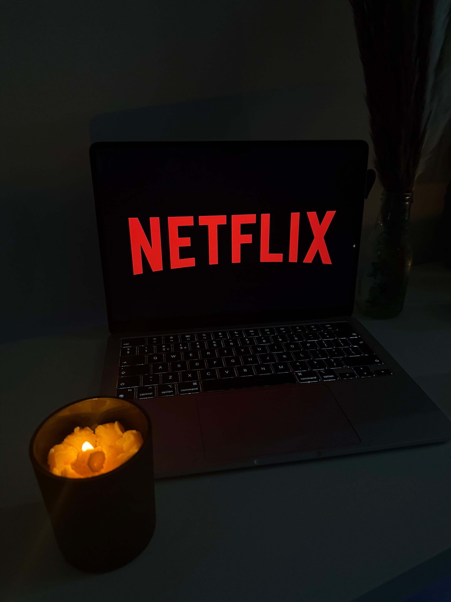 Popcorn theme candle beside a laptop displaying the Netflix logo, perfect for cozy movie date nights.