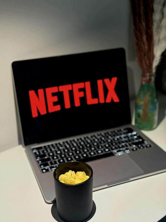 Popcorn theme candle next to a laptop with Netflix logo, perfect for movie date nights.